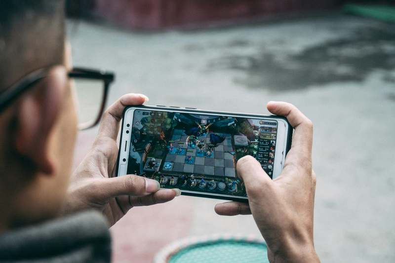 Two adults casually playing mobile games on their phones in a relaxed lounge setting